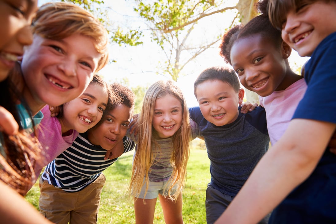 Group of Smiling Schoolchildren Lean in to Camera Embracing